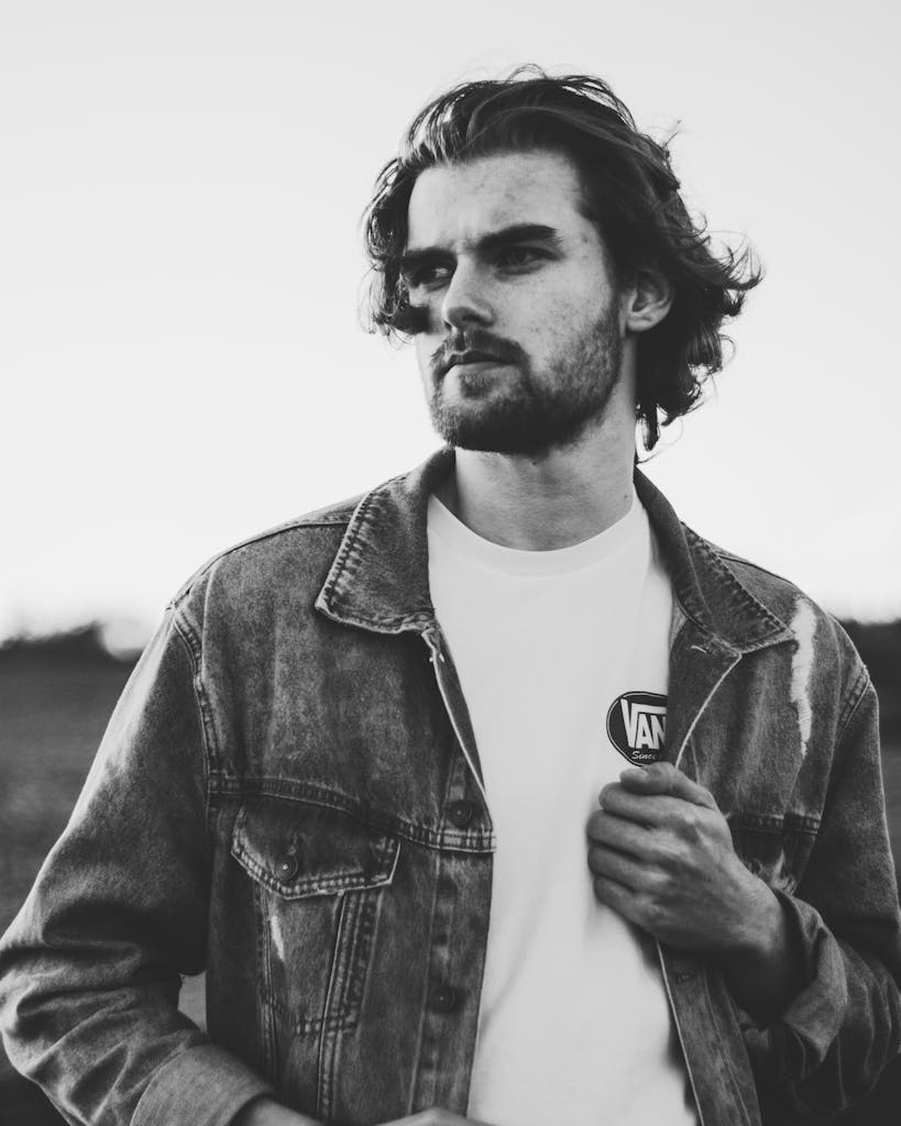 Artistic black and white portrait of a man in denim with expressive pose.